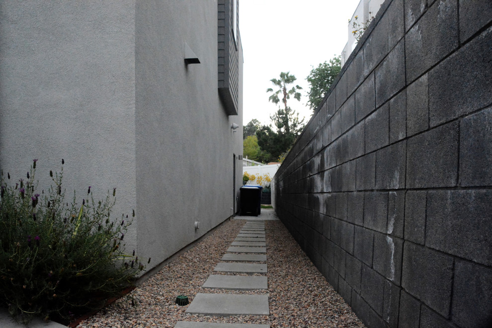 Idee per un giardino xeriscape contemporaneo esposto a mezz'ombra di medie dimensioni e nel cortile laterale in estate con un muro di contenimento e pavimentazioni in cemento
