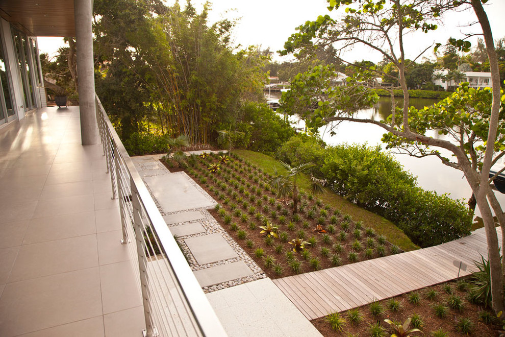 Diseño de camino de jardín tropical de tamaño medio en invierno en patio delantero con exposición total al sol y adoquines de hormigón