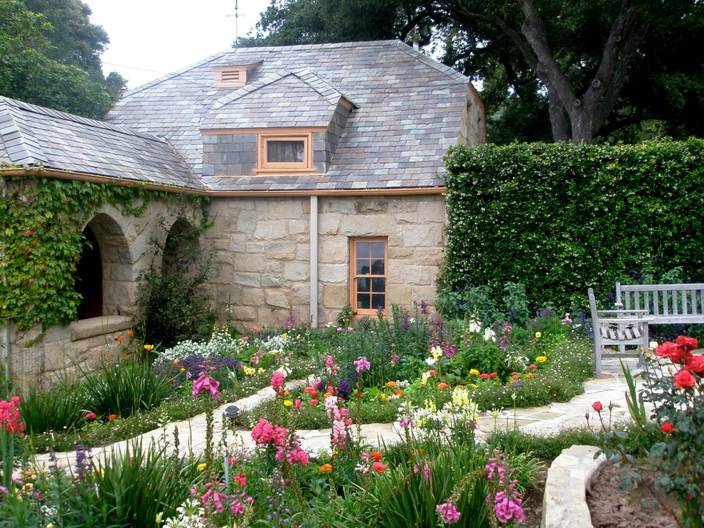Geometrischer Landhausstil Garten im Sommer, hinter dem Haus mit Natursteinplatten und Blumenbeet in Santa Barbara