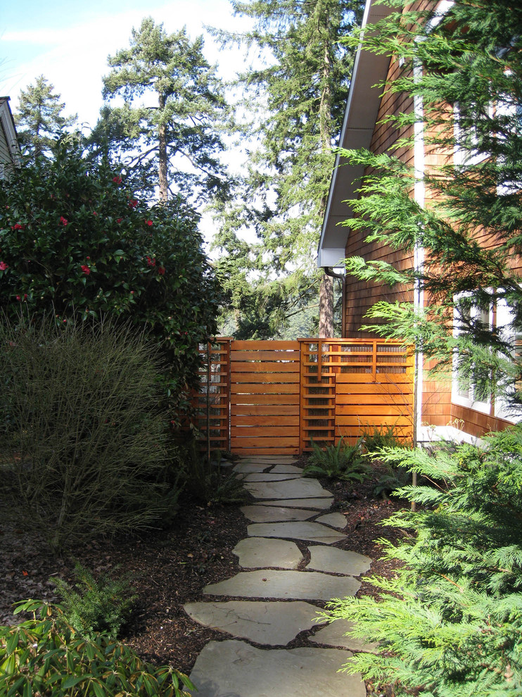 Exempel på en modern trädgård i skuggan längs med huset, med naturstensplattor