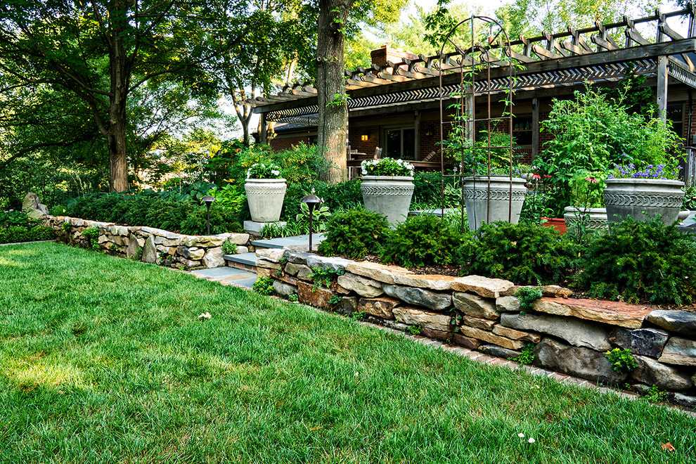 Photo of a mid-sized traditional partial sun backyard stone retaining wall landscape in DC Metro for summer.