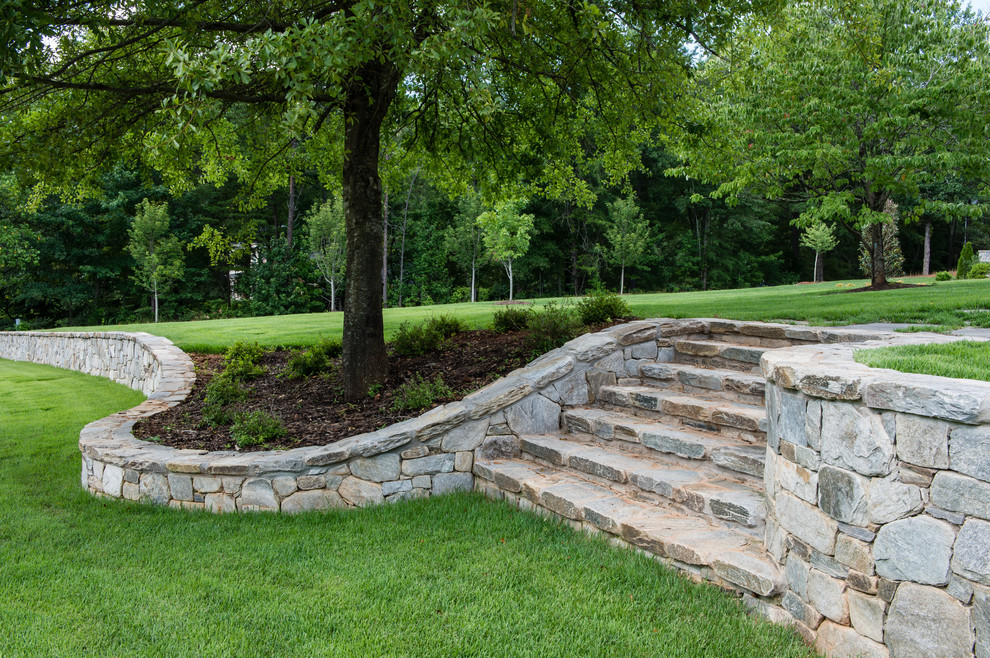 This is an example of a medium sized traditional front partial sun garden in Charlotte with a retaining wall and natural stone paving.