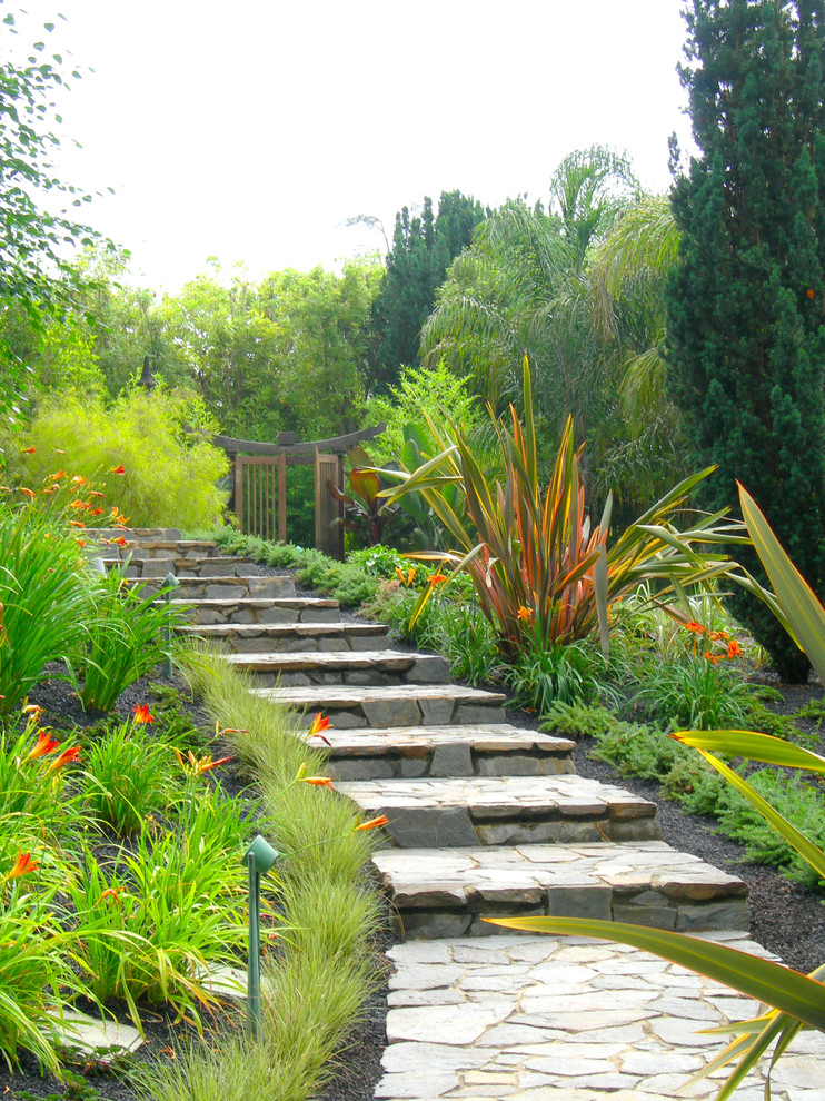 Réalisation d'un jardin tradition avec une pente, une colline ou un talus et des pavés en pierre naturelle.