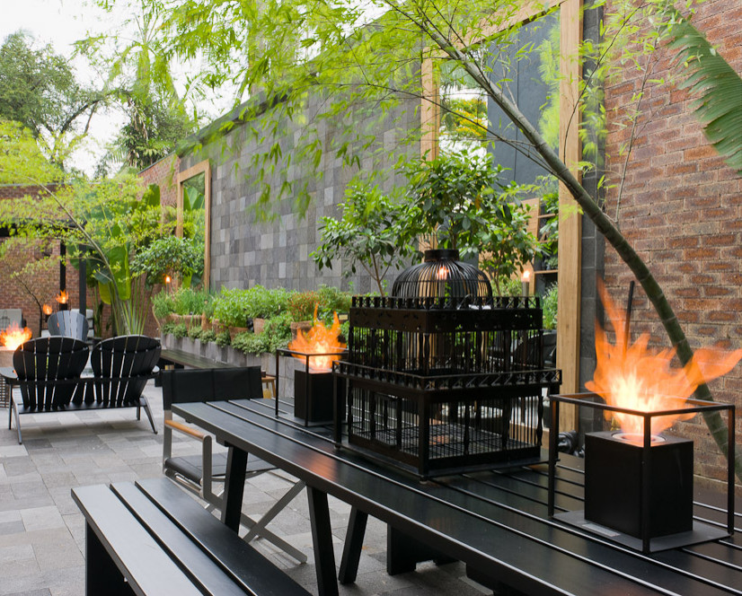 Expansive industrial courtyard formal partial sun garden with a fireplace.