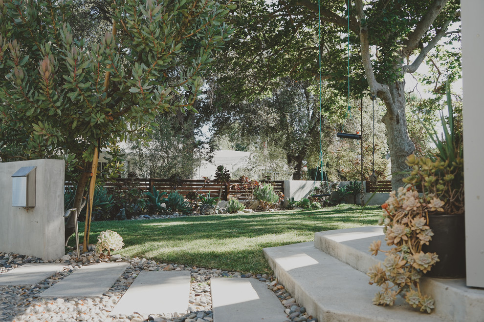 Ejemplo de jardín de secano moderno grande en patio delantero con muro de contención, exposición reducida al sol y gravilla