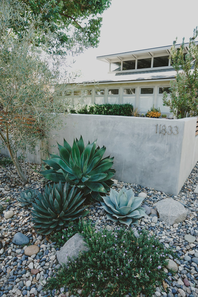 Пример оригинального дизайна: большой тенистый засухоустойчивый сад на переднем дворе в стиле модернизм с подпорной стенкой и покрытием из гравия