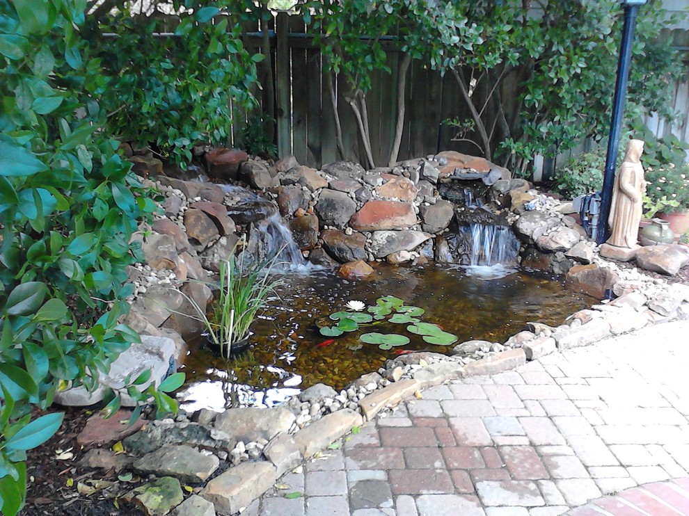 Small back partial sun garden in Austin with a water feature and brick paving.