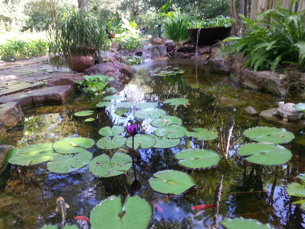 This is an example of a mid-sized partial sun backyard brick water fountain landscape in Austin.