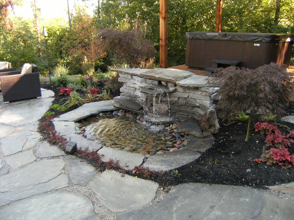 Exempel på en mellanstor eklektisk bakgård, med en fontän och naturstensplattor