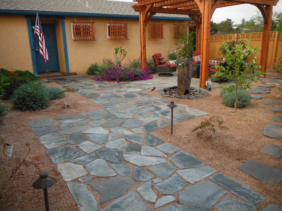 Large traditional front full sun garden for summer in San Diego with a water feature and gravel.