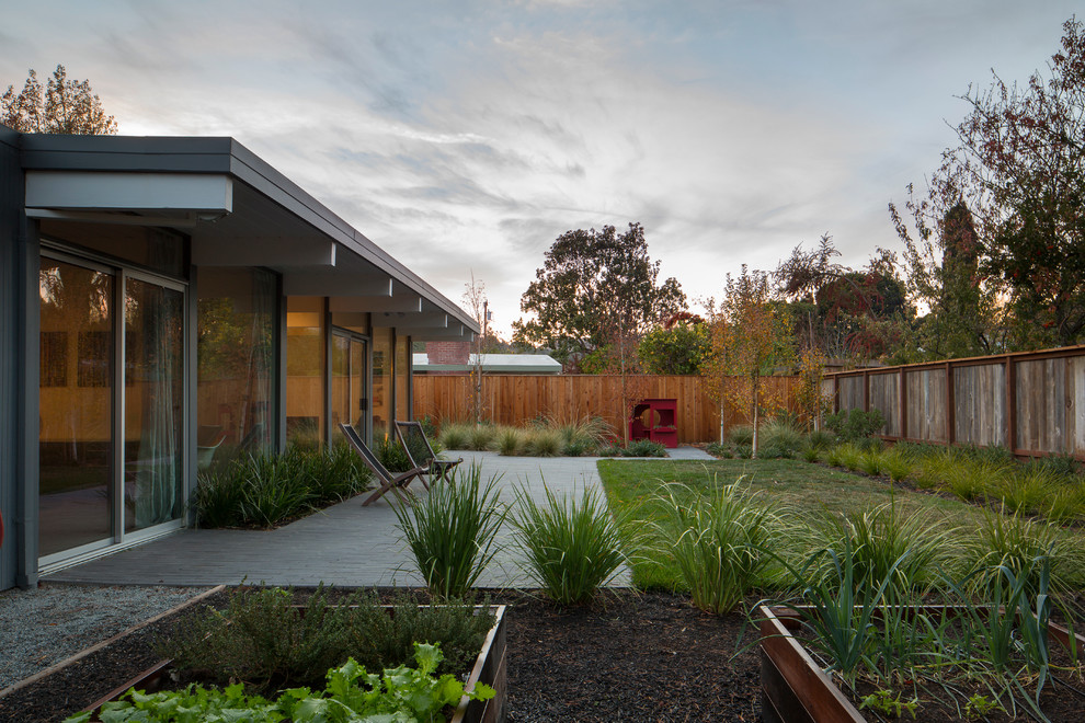 Пример оригинального дизайна: огромный солнечный, летний участок и сад на заднем дворе в стиле ретро с хорошей освещенностью, мощением тротуарной плиткой и с деревянным забором