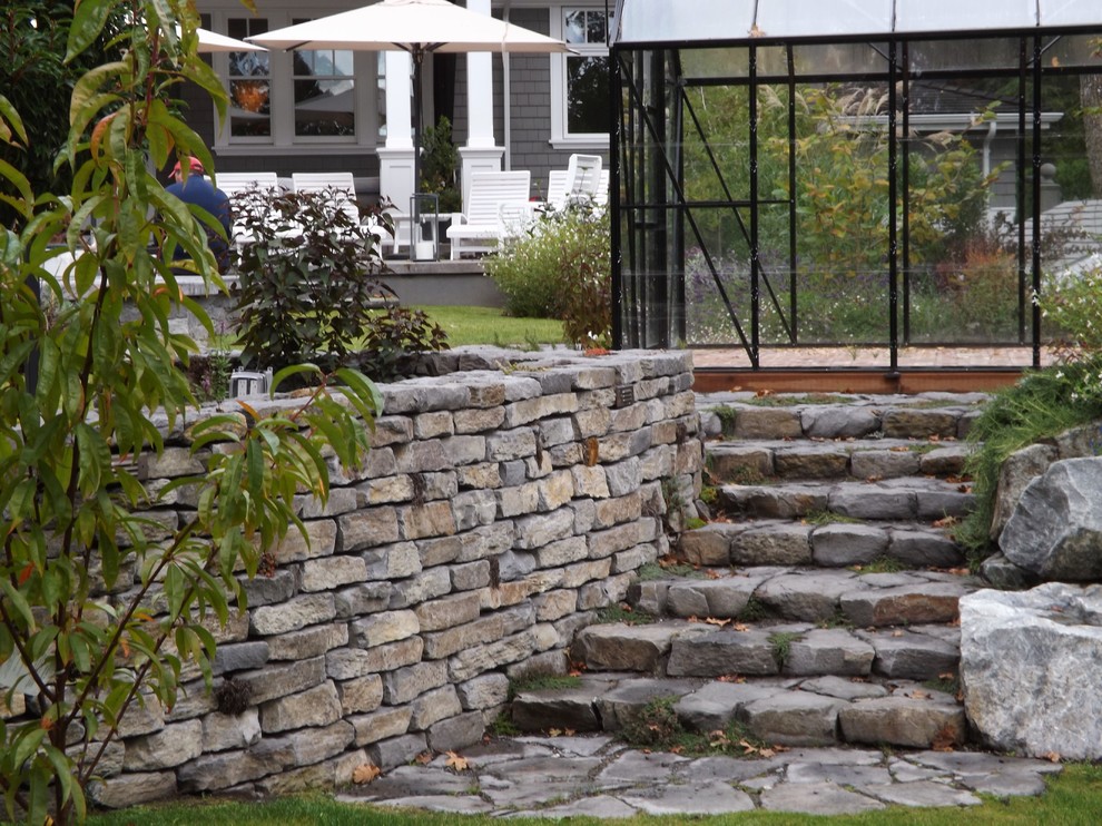 Foto di un ampio giardino xeriscape stile marinaro esposto in pieno sole dietro casa con un muro di contenimento e pavimentazioni in pietra naturale