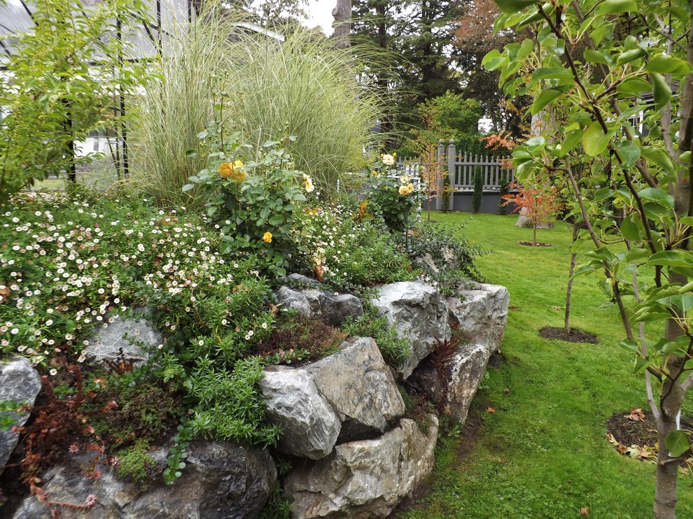 Ispirazione per un ampio giardino xeriscape stile marinaro esposto in pieno sole dietro casa con un muro di contenimento e pavimentazioni in pietra naturale