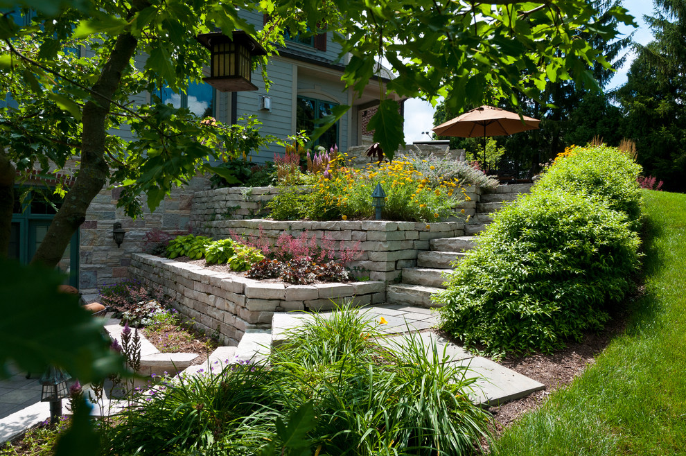 Immagine di un giardino classico esposto in pieno sole di medie dimensioni in estate con un muro di contenimento e pavimentazioni in pietra naturale