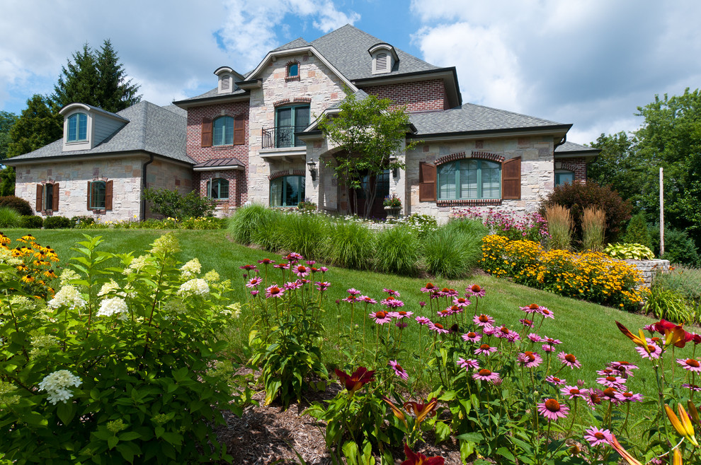 Esempio di un giardino classico esposto in pieno sole di medie dimensioni e davanti casa in estate con un muro di contenimento e pavimentazioni in pietra naturale