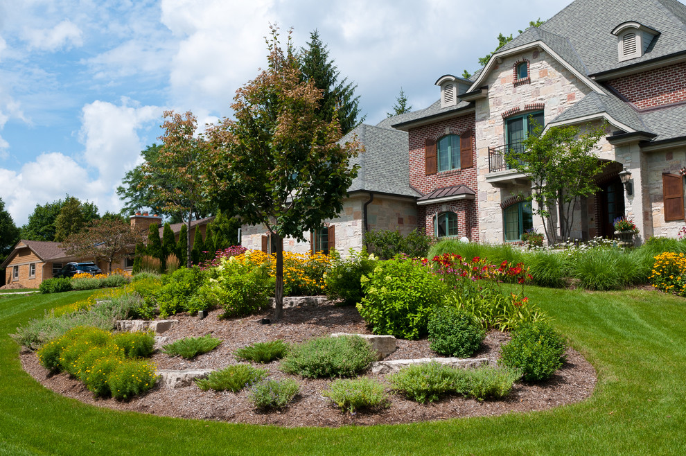 Inspiration for a mid-sized traditional full sun front yard stone retaining wall landscape in Milwaukee for summer.