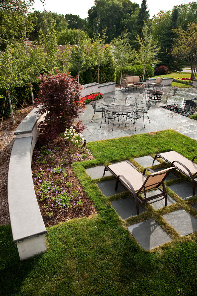 Foto di un giardino minimalista esposto in pieno sole di medie dimensioni e dietro casa in estate con pavimentazioni in pietra naturale e un muro di contenimento