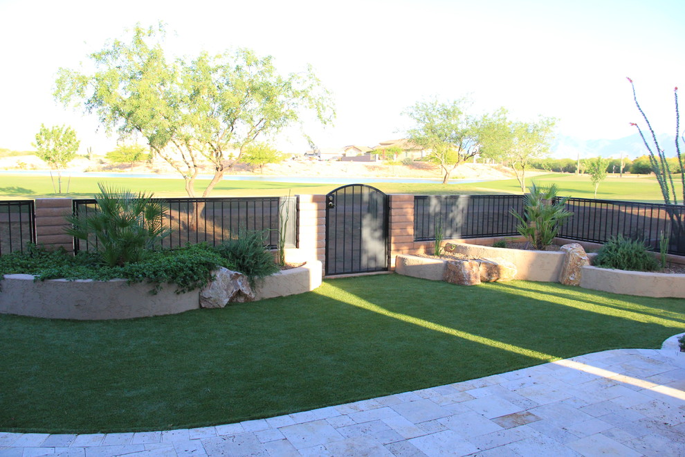 Medium sized mediterranean back xeriscape partial sun garden for summer in Phoenix with a retaining wall and natural stone paving.
