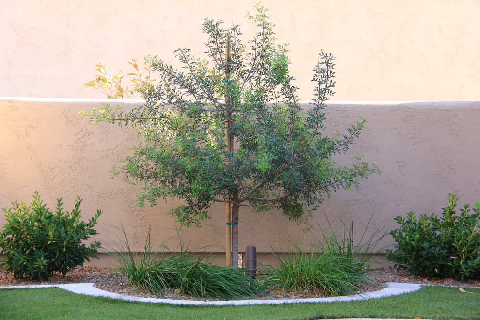 This is an example of a mid-sized mediterranean drought-tolerant and shade side yard stone landscaping in Phoenix for summer.
