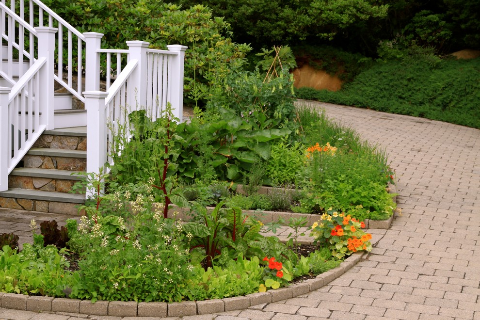 Imagen de jardín clásico en verano en patio lateral con adoquines de ladrillo, huerto y exposición total al sol