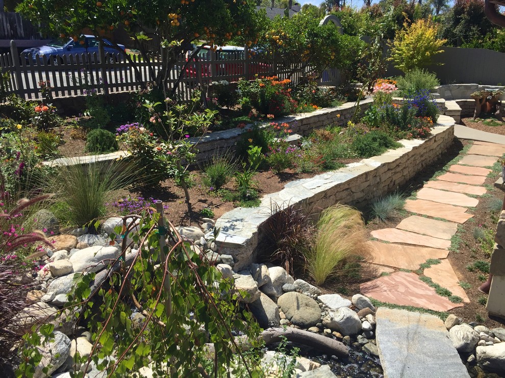 Immagine di un giardino formale country esposto in pieno sole di medie dimensioni e davanti casa in primavera con un muro di contenimento e pavimentazioni in pietra naturale