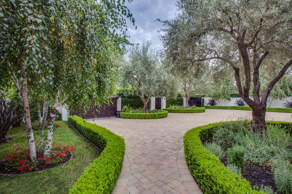 На фото: участок и сад на переднем дворе в средиземноморском стиле с подъездной дорогой и покрытием из каменной брусчатки с
