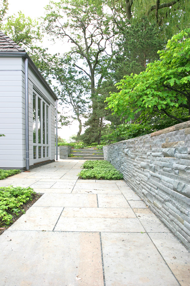 Foto de jardín clásico renovado de tamaño medio en patio lateral con muro de contención y adoquines de hormigón