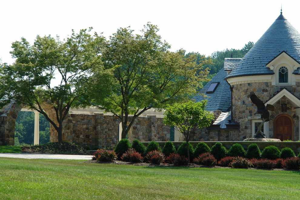 This is an example of an expansive rural front full sun garden for spring in Philadelphia with an outdoor sport court and natural stone paving.