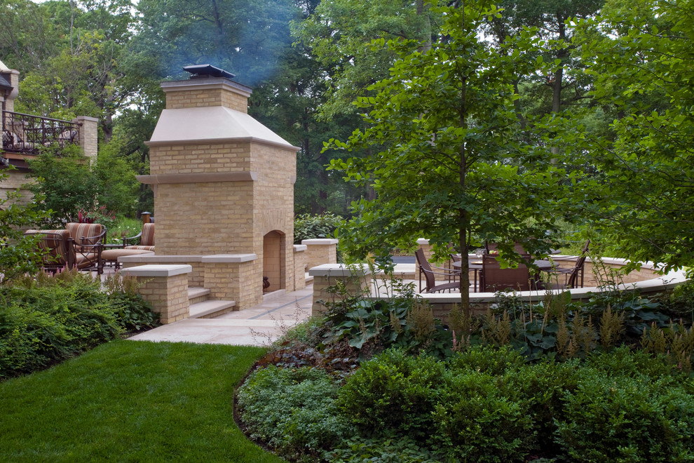 Modelo de jardín clásico grande en verano en patio trasero con brasero, exposición reducida al sol y adoquines de piedra natural