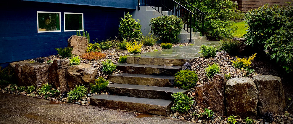 This is an example of a rustic front partial sun garden steps in Vancouver with decorative stones.
