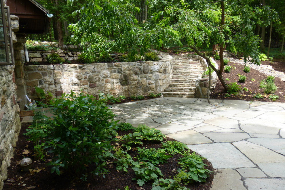 Esempio di un giardino xeriscape stile rurale esposto a mezz'ombra in cortile in estate con un muro di contenimento e pavimentazioni in pietra naturale