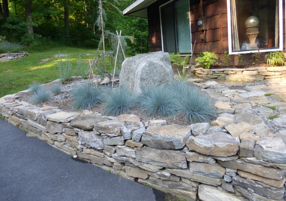 This is an example of a medium sized rustic full sun garden for summer in New York with a retaining wall.