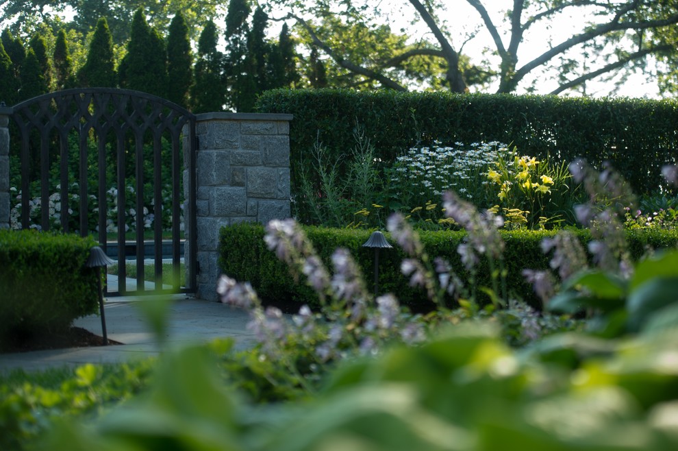Ispirazione per un giardino formale chic esposto a mezz'ombra di medie dimensioni e dietro casa con pavimentazioni in pietra naturale