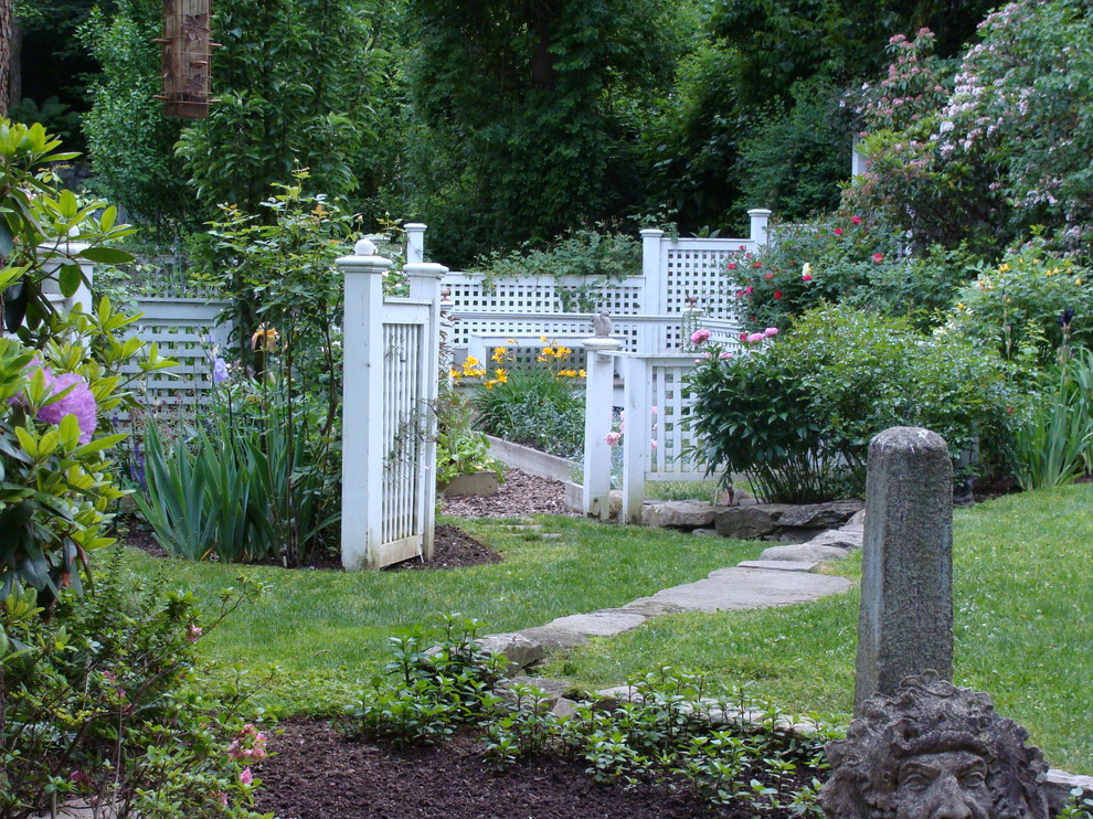 Réalisation d'un jardin arrière tradition de taille moyenne avec des pavés en pierre naturelle et une clôture en vinyle.