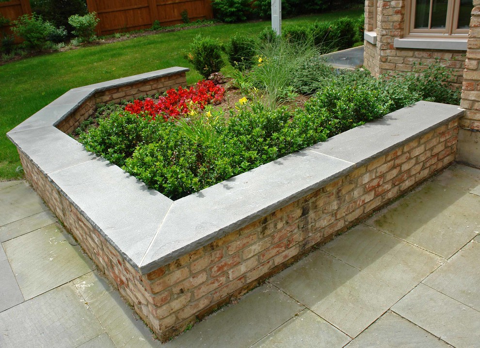 Ejemplo de jardín clásico grande en patio trasero con brasero y adoquines de piedra natural