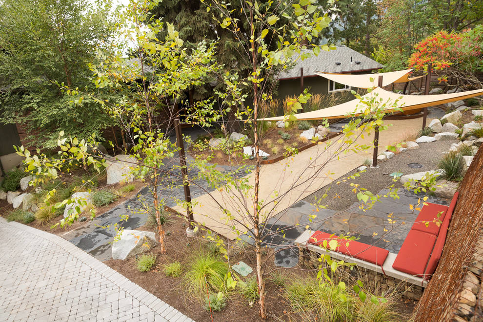 Idee per un grande giardino xeriscape moderno esposto in pieno sole davanti casa con un muro di contenimento e pavimentazioni in cemento