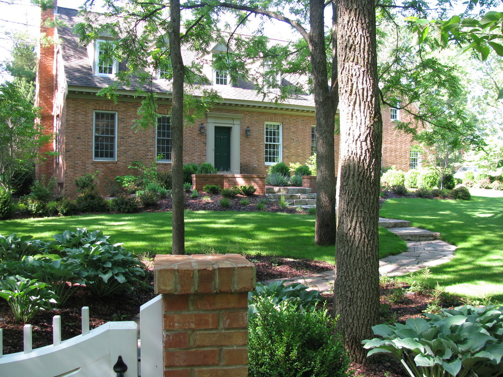 This is an example of a large traditional front formal partial sun garden for spring in Detroit with a garden path and brick paving.