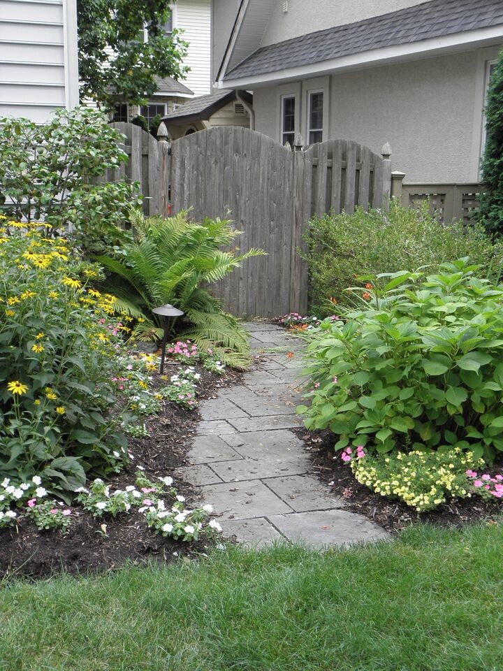 Small traditional side formal full sun garden for spring in New York with a garden path and natural stone paving.