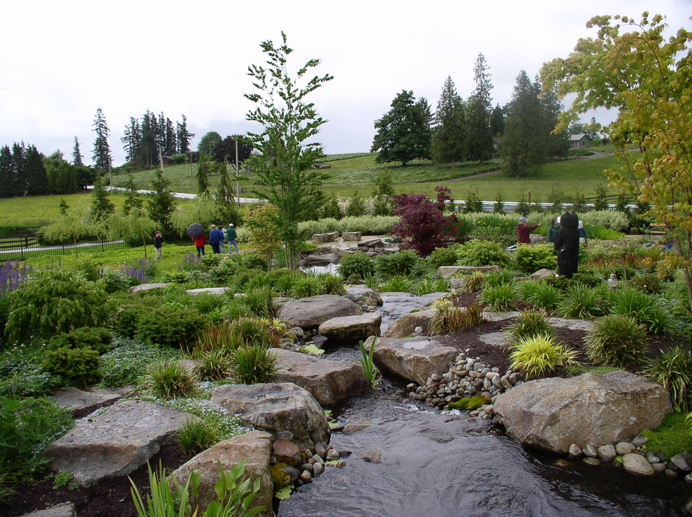 Cette photo montre un très grand jardin nature avec un point d'eau, une exposition ensoleillée, une pente, une colline ou un talus et des pavés en pierre naturelle.