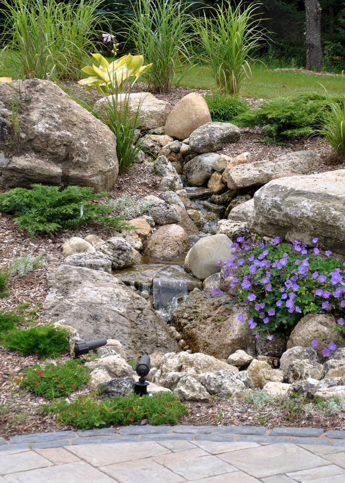 Inspiration pour un grand jardin arrière traditionnel au printemps avec une exposition ensoleillée, des pavés en béton et une cascade.