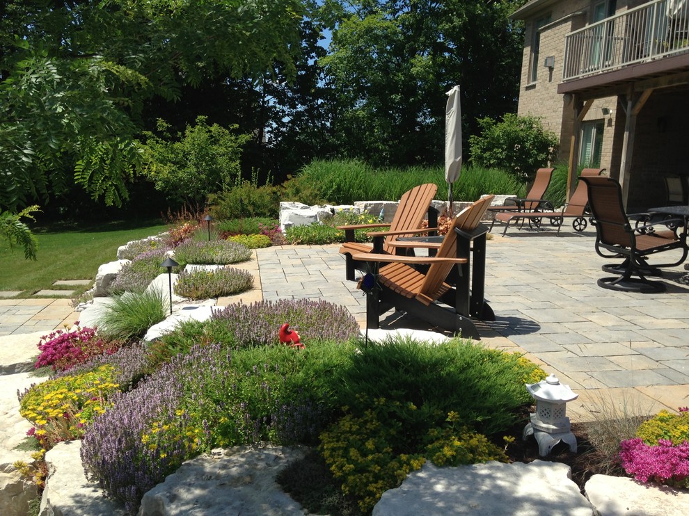 This is an example of a medium sized traditional back formal partial sun garden for spring in Toronto with natural stone paving.