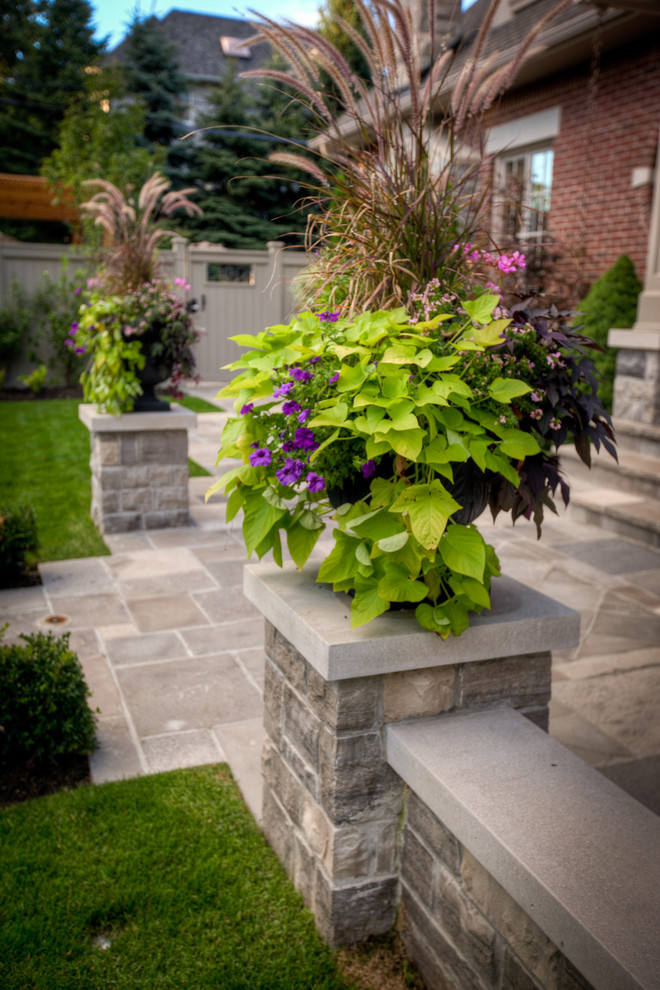 This is an example of a large contemporary side partial sun garden for summer in Toronto with a garden path and natural stone paving.