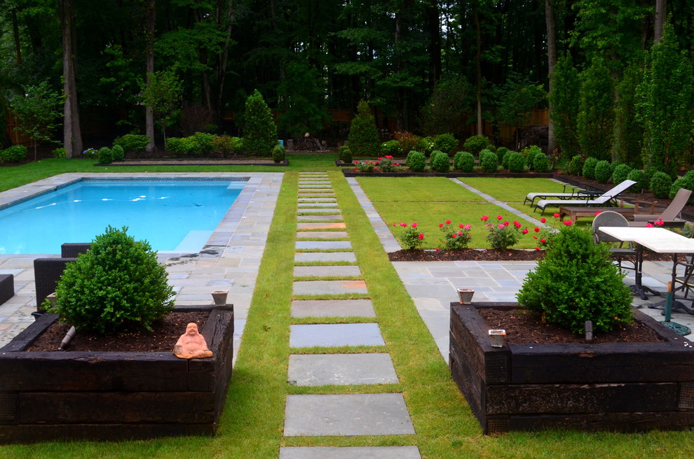 Aménagement d'un grand jardin à la française arrière contemporain l'été avec des pavés en pierre naturelle et une exposition partiellement ombragée.