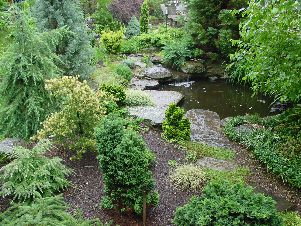 Réalisation d'un grand jardin arrière tradition avec un bassin, une exposition partiellement ombragée et des pavés en pierre naturelle.