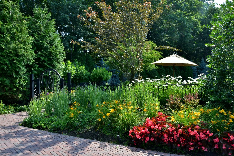 Foto de jardín tropical de tamaño medio en verano en patio trasero con jardín francés, exposición parcial al sol y adoquines de hormigón