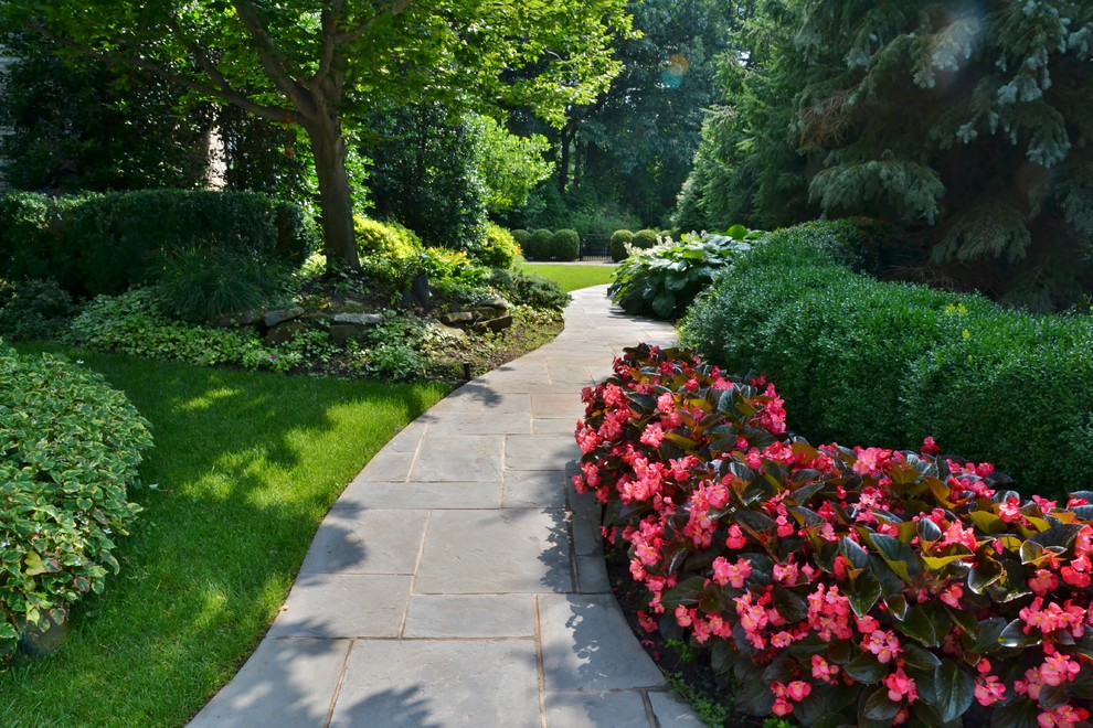 Photo of a mid-sized tropical partial sun side yard concrete paver garden path in New York for summer.