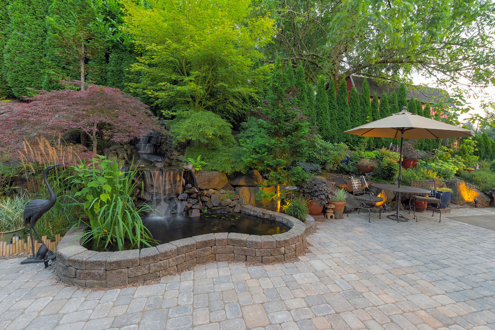 Cette image montre un jardin traditionnel avec un point d'eau et des pavés en pierre naturelle.
