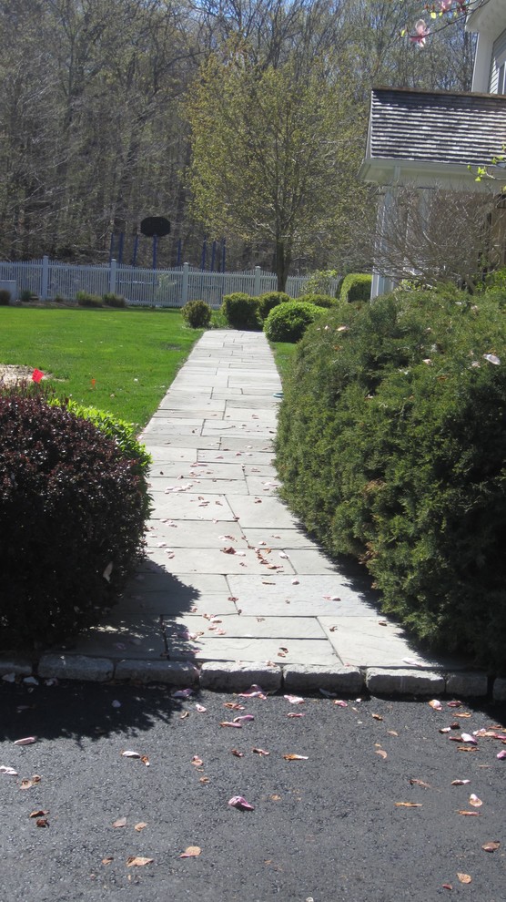 Exempel på en stor klassisk uppfart framför huset, med en trädgårdsgång och naturstensplattor