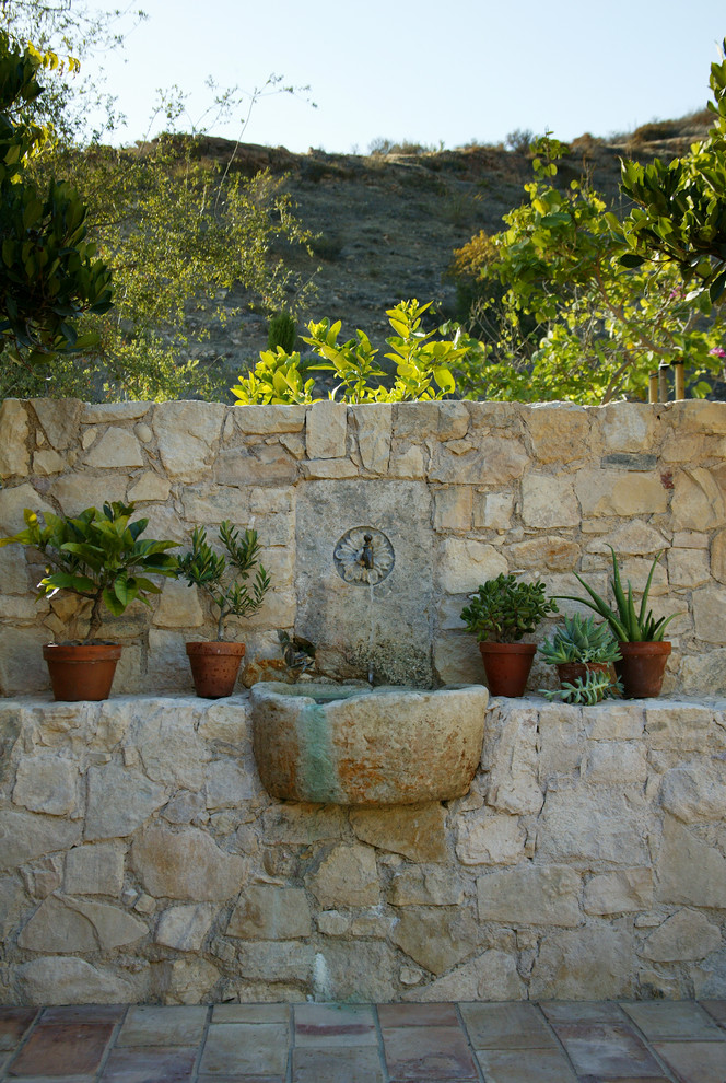 This is an example of a small mediterranean full sun backyard stone formal garden in Orange County for summer.