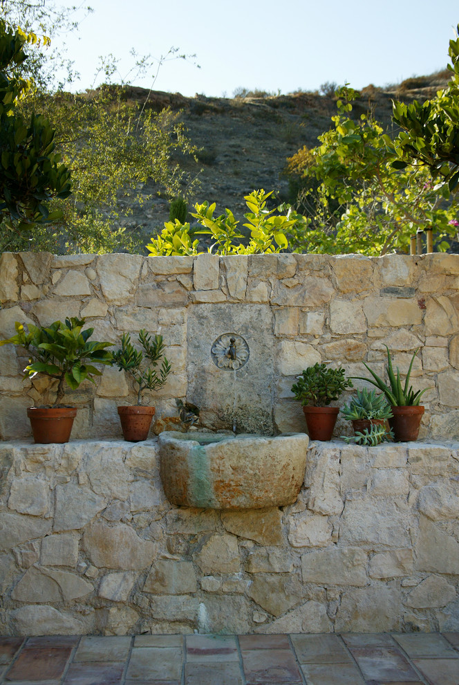 Foto de jardín mediterráneo pequeño en verano en patio trasero con jardín francés, exposición total al sol y adoquines de piedra natural